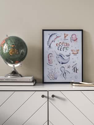 Framed ocean life poster on a cabinet beside a globe