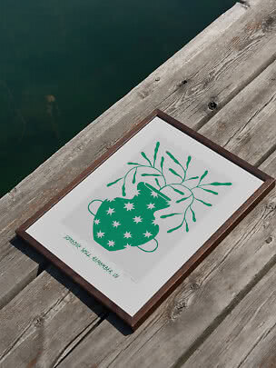 Framed poster with green abstract flower on a wooden dock by the water