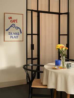 Dining corner with round table, vase of flowers, mugs and French poster on the wall