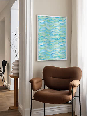 Abstract wall art with blue and green waves in a white frame above a brown armchair