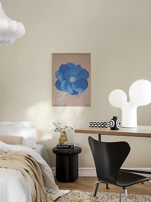 Dormitorio con póster de flor azul sobre la cama, escritorio, silla negra y lámpara blanca