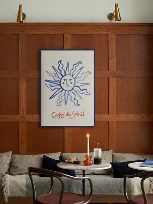 Poster con sole blu e scritta "Café du Soleil" sopra una panca e un piccolo tavolo da caffè