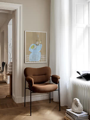 Brauner Polsterstuhl mit schwarzen Beinen an einem hellen Fenster in stilvollem Raum
