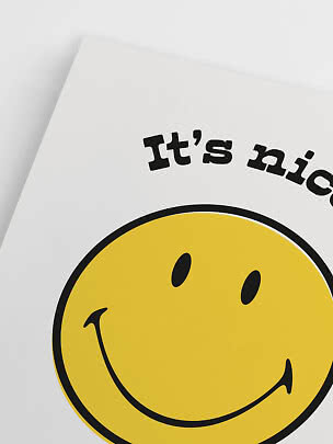 Close-up of poster with yellow smiley face and text "It's nic..." on white background