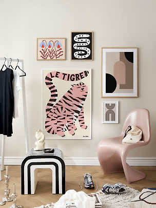Coin élégant avec mur de cadres, chaise rose, tabouret noir et blanc et portant