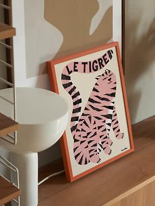 Affiche encadrée avec un tigre rose et le texte « Le Tigre » sur une étagère en bois