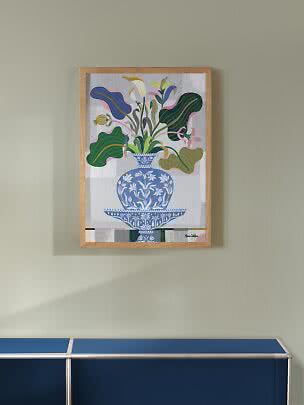 Ingelijste kunstprint met kleurrijke bloemen in blauwe vaas aan lichtgroene muur