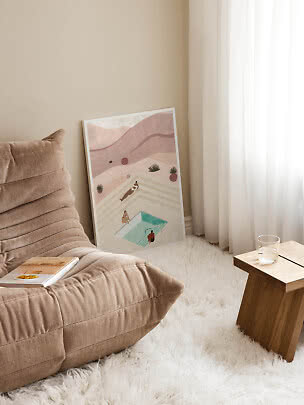 Framed art print with abstract pool scene leaning against the wall in a bright living room