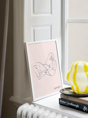 Framed minimalist line drawing on a pink background, leaning on a windowsill