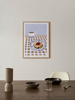 Poster incorniciato con dolce alla panna e lamponi e una tazza su tovaglia a quadri
