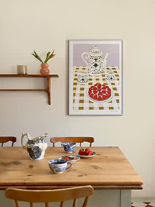 Poster met theepot en aardbeientaart boven een houten tafel met blauw-witte kan, kop en aardbeien.