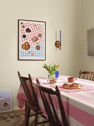 Eethoek met roze gestreept tafelkleed, houten stoelen, tulpen en bord met kaneelbroodjes.