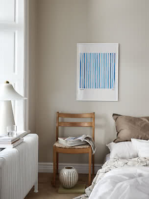 Camera da letto con poster a righe blu in cornice bianca sopra una sedia in legno
