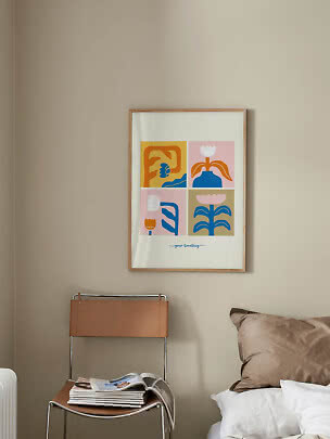 Ingelijste kleurrijke bloemenprint aan beige muur boven stoel naast bed