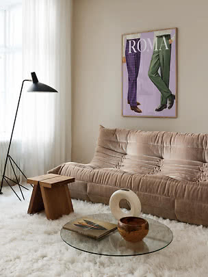 Cozy living room with beige sofa, black floor lamp, glass table and Roma poster on the wall