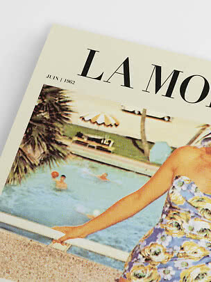 Angled close-up of a vintage poster showing a pool scene and woman in a floral swimsuit