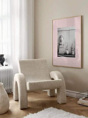 Poster d’arte incorniciato con passe-partout rosa e foto in bianco e nero di statua sopra una poltrona beige