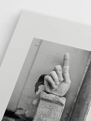 Schwarzweiß-Poster einer skulptierten Hand auf Sockel mit erhobenem Mittelfinger