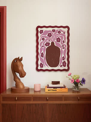 Arte de pared con jarrón marrón y patrón floral morado sobre aparador de madera