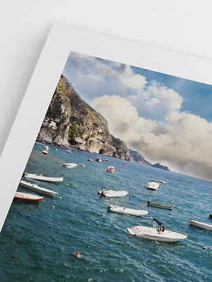 Framed photo print of a coastal cliff with boats on the sea under a cloudy sky