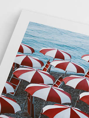 Foto incorniciata di spiaggia con ombrelloni rossi e bianchi sul mare