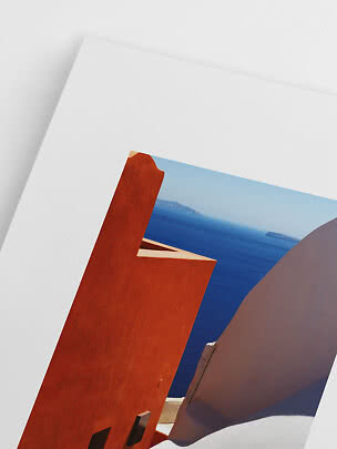 Poster with white border showing orange and white buildings by a blue sea