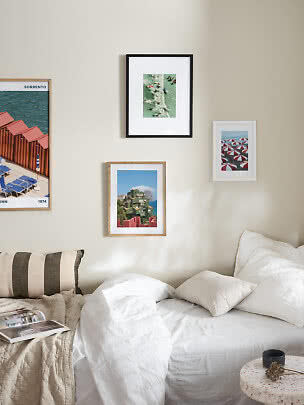 Bright bedroom with white bed, pillows, striped cushion and four framed wall prints