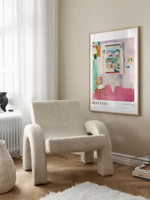 Gerahmtes Matisse-Poster an beigefarbener Wand über cremefarbenem Sessel am Fenster