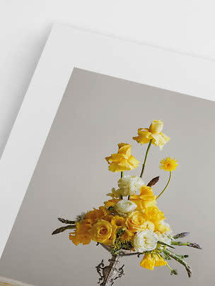 Gul og hvid blomsterbuket i dekorativ sølvvase mod lys grå væg