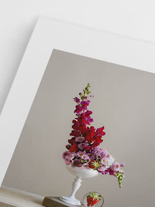 Asymmetrisches Blumenarrangement in weißer Vase mit rosa, roten Blüten und Erdbeeren