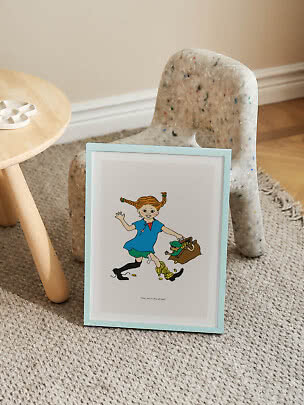 Poster di Pippi con cornice azzurra su tappeto accanto a uno sgabello in legno e una piccola sedia
