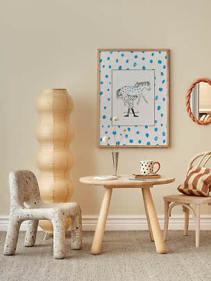 Coin cosy avec petite table en bois, lampe en papier, chaise et affiche encadrée à pois bleus