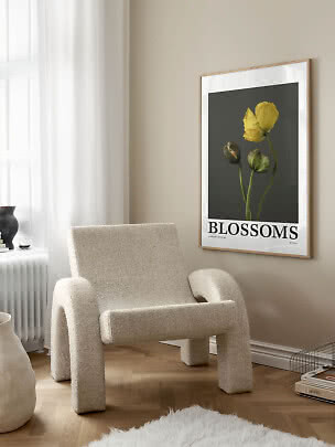 Affiche florale encadrée avec fleur jaune sur fond sombre au-dessus d’un fauteuil crème