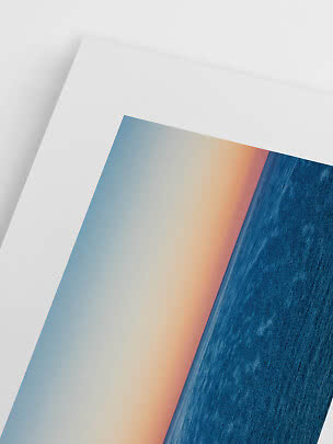 Primer plano de lámina abstracta con bloques azules y tonos cálidos sobre papel blanco