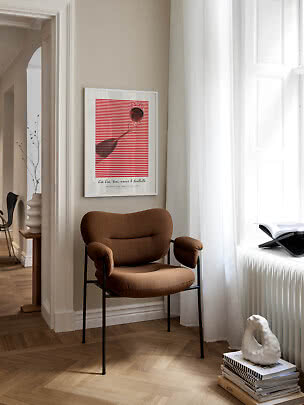 Brauner Polsterstuhl mit schwarzen Beinen in heller Ecke neben Fenster und Wandbild