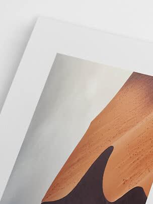 Nærbillede af indrammet plakat med abstrakt sandklit i varme bruntoner
