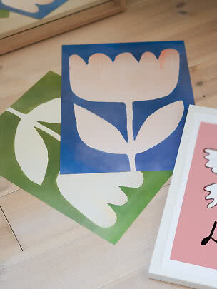 Abstract floral posters in blue, green and pink on a wooden floor