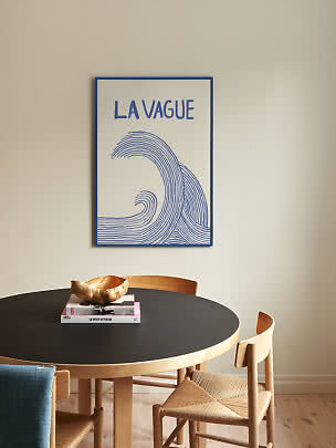 Blue and white wave poster with the text "La Vague" above a round black dining table.