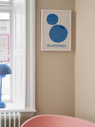 Inramad poster med två blå blåbär och texten "BLUEBERRIES" på beige vägg