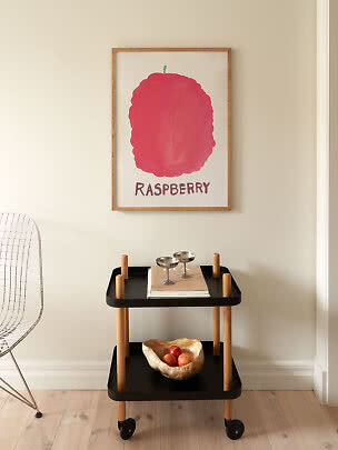 Poster incorniciato con grande illustrazione rosa di lampone sopra carrello nero