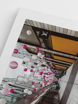 Überdachte Ladenpassage mit hängenden rosa-weißen Laternen und Louis-Vuitton-Schild