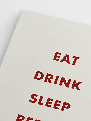 Nærbillede af hvid plakat med røde ord, herunder "EAT", "DRINK" og "SLEEP"