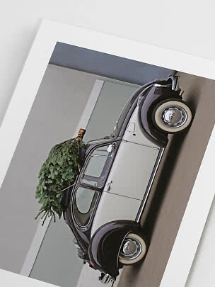 Auto vintage bianca e nera con albero di Natale sul tetto, mostrata su stampa inclinata