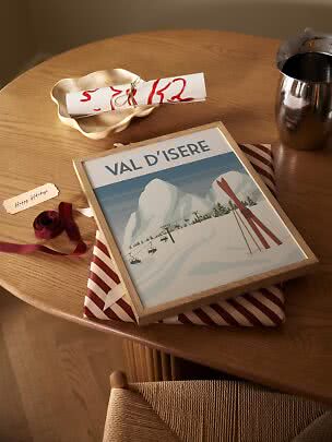 Indrammet Val d’Isère-skiplakat på indpakket gave på træbord med bånd og metalkop