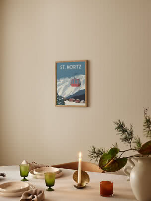 Affiche encadrée St. Moritz sur mur beige au-dessus d'une table dressée avec bougie