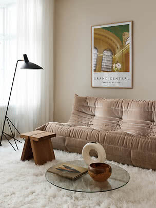 Stue med brun sofa, sort gulvlampe og indrammet Grand Central-plakat på beige væg