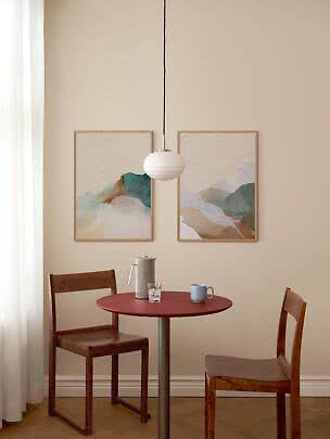 White ribbed pendant lamp above a round red table with two wooden chairs in a bright dining nook