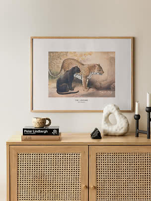 Póster enmarcado de leopardo con un leopardo y una pantera negra sobre un mueble de madera clara