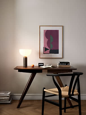 Donker houten bureau met brandende tafellamp, stoel en abstracte poster aan de muur
