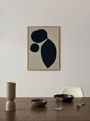 Ingelijste abstracte poster met zwarte organische vormen boven een eettafel